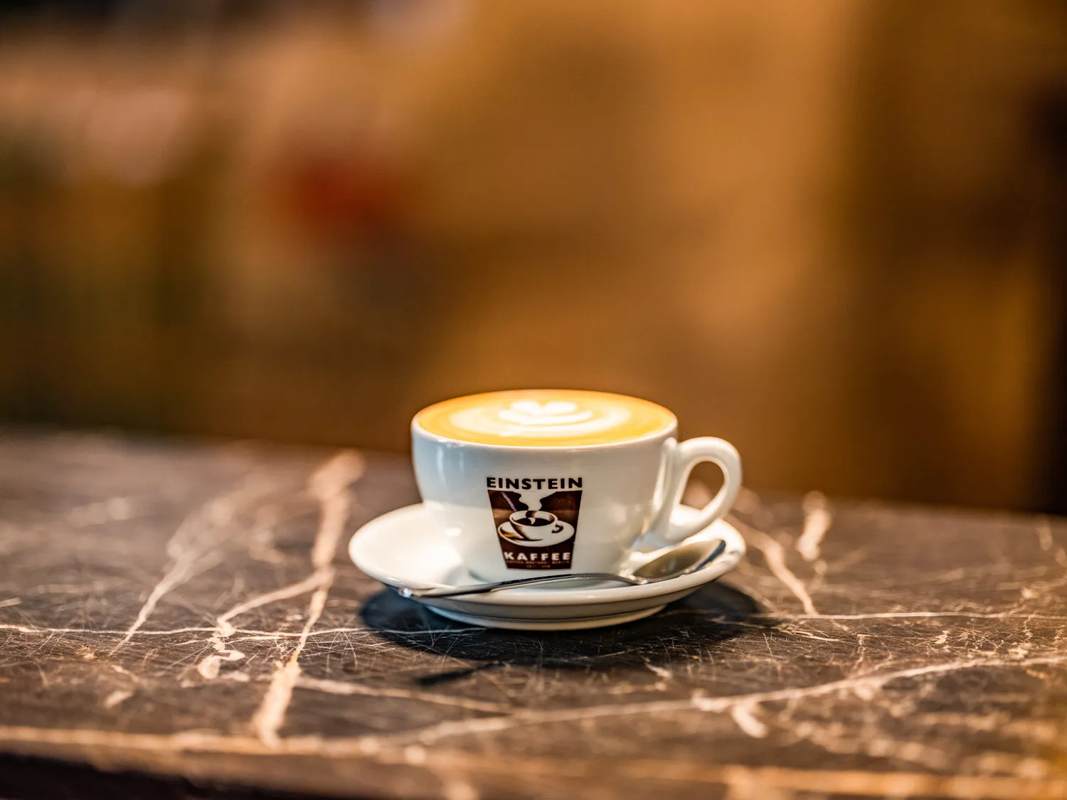 Cappuccino mit Latte Art in einer Einstein-Kaffee-Tasse auf Marmortheke